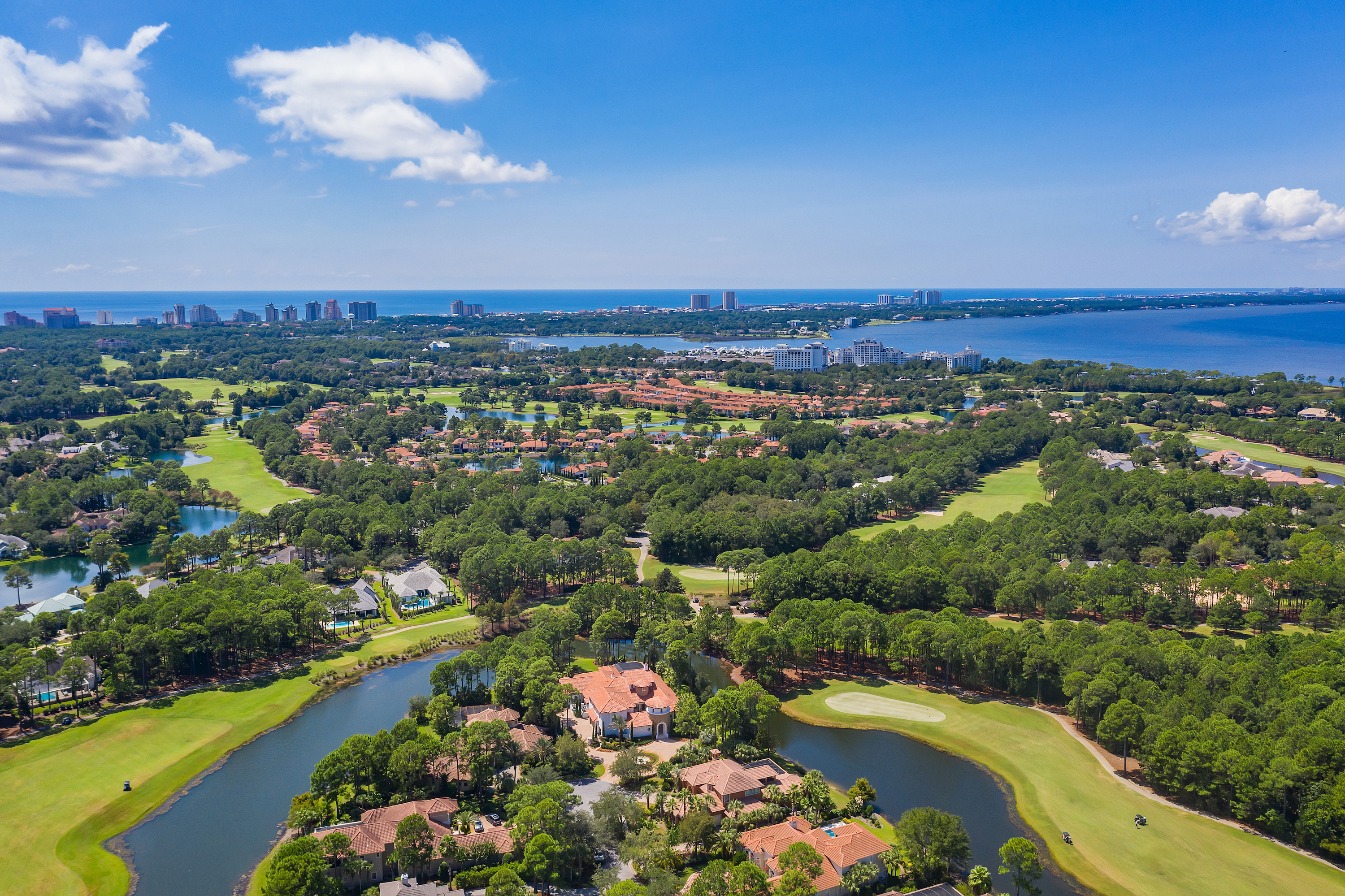 An aerial view of Sandestin homes and golf course with Choctawhatchee Bay in the background on a blue sky day