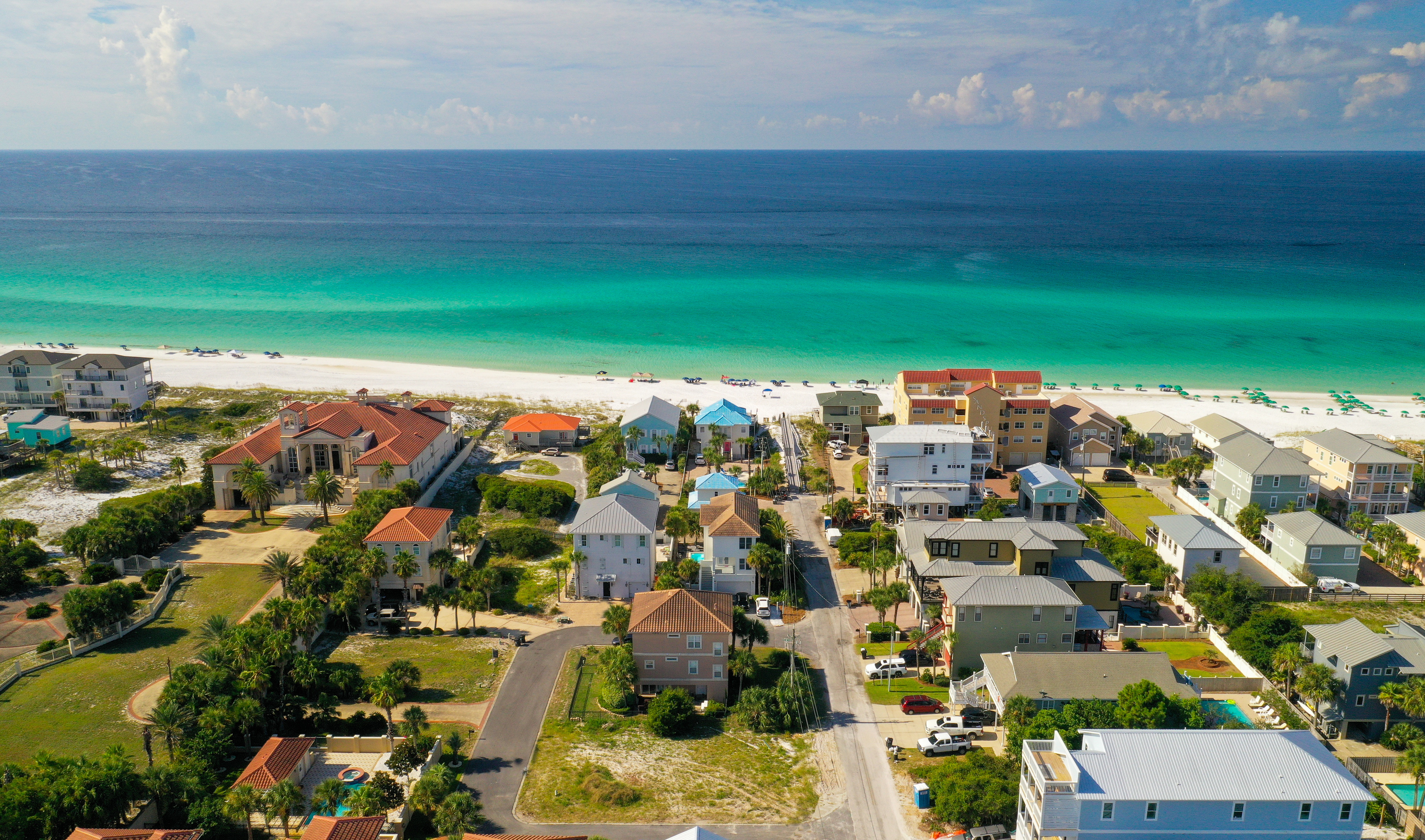An aerial view of homes and land in Miramar Beach with the brilliant blue gulf waters in the background