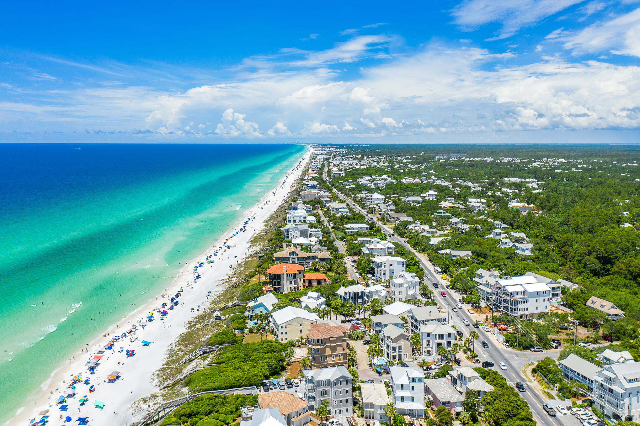 An aerial view of Seagrove Beach with homes and businesses along the gulf shoreline on a sunny day featuring brilliant clear blue waters