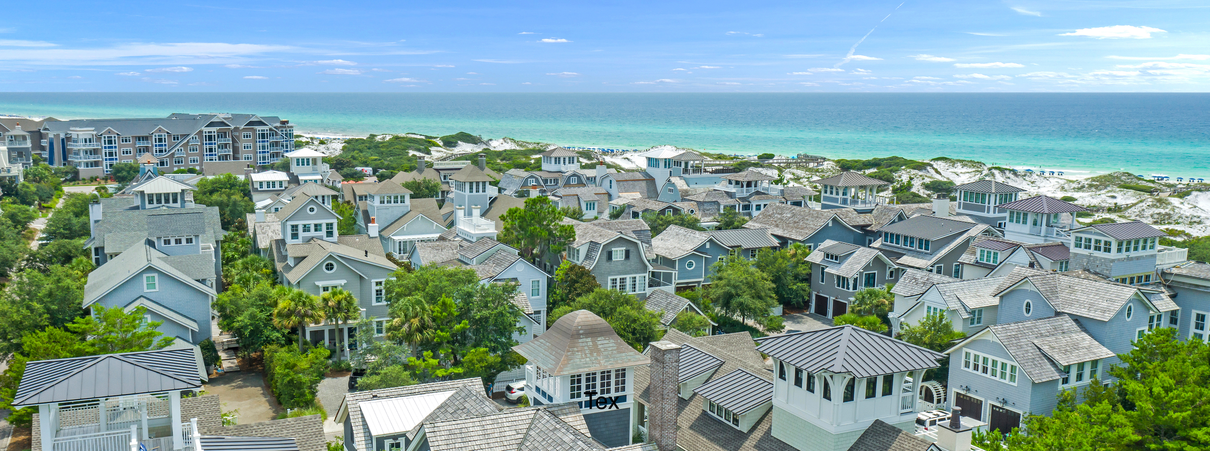 An aerial view of homes at Watersound West Beach with the gulf in the background on a pleasant sunny day