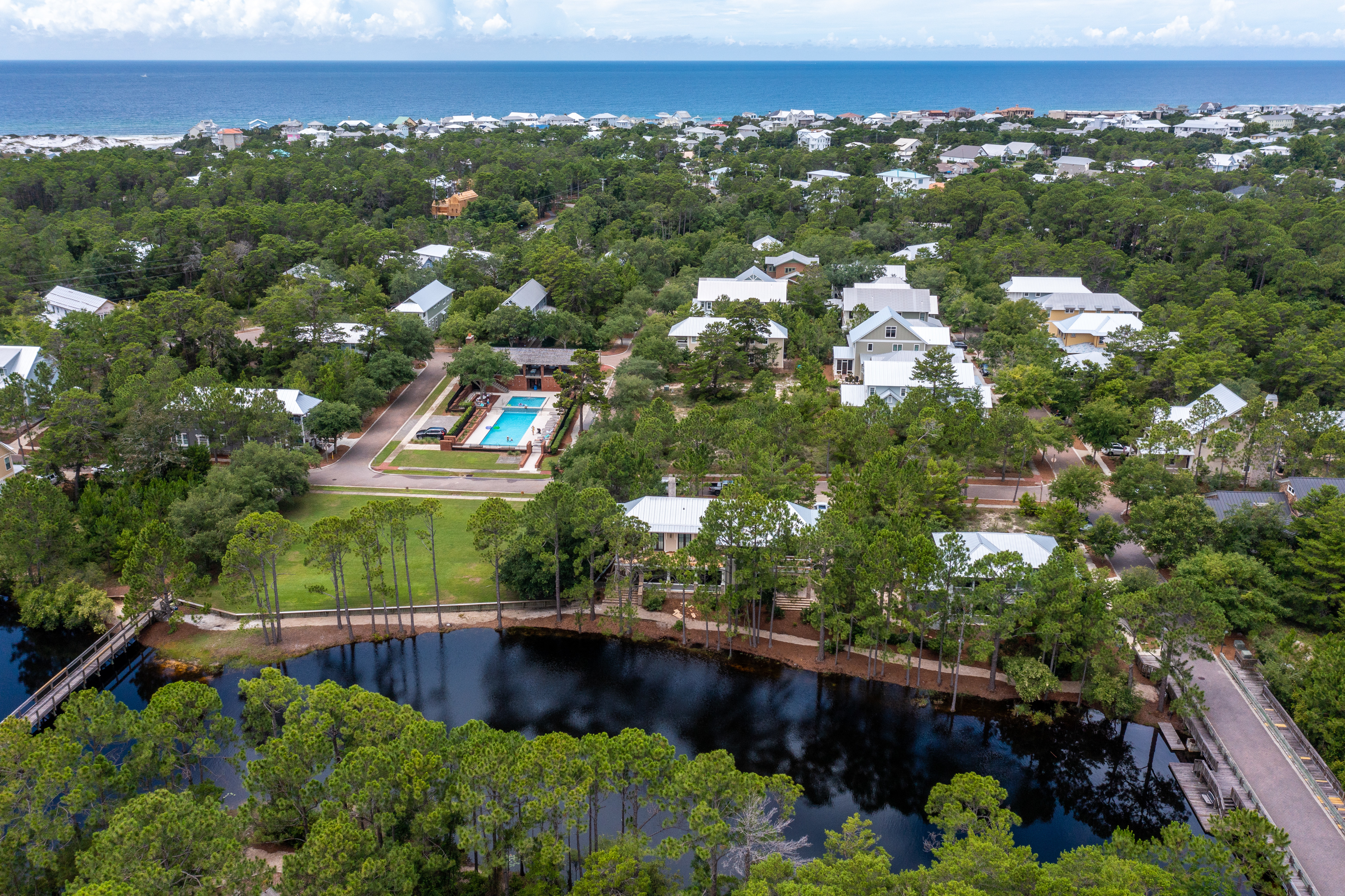 An aerial view of the Forest Lakes community featuring the lake, community pool and the Gulf