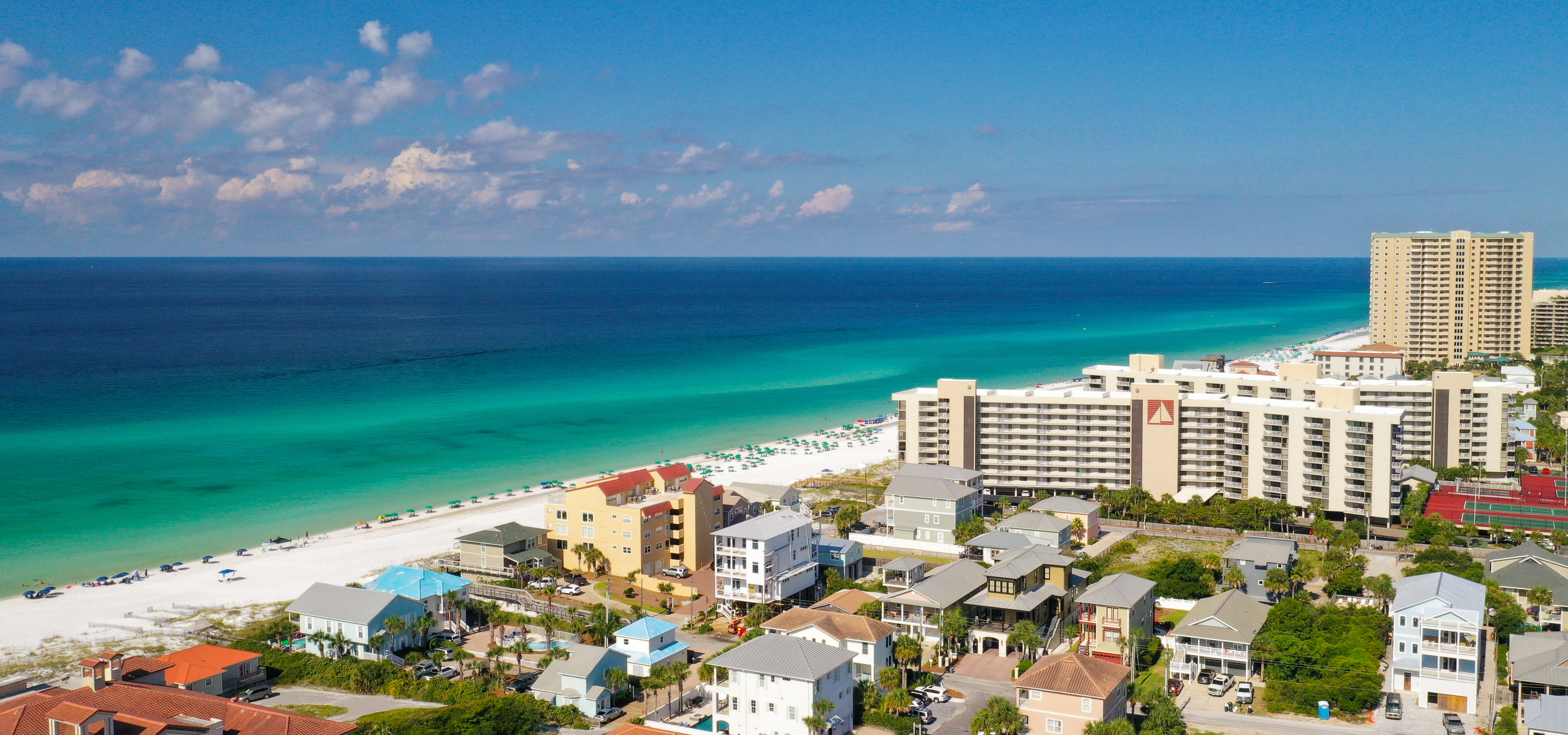 An aerial view of condos along the beach in Miramar Beach parallel to turquoise blue gulf waters
