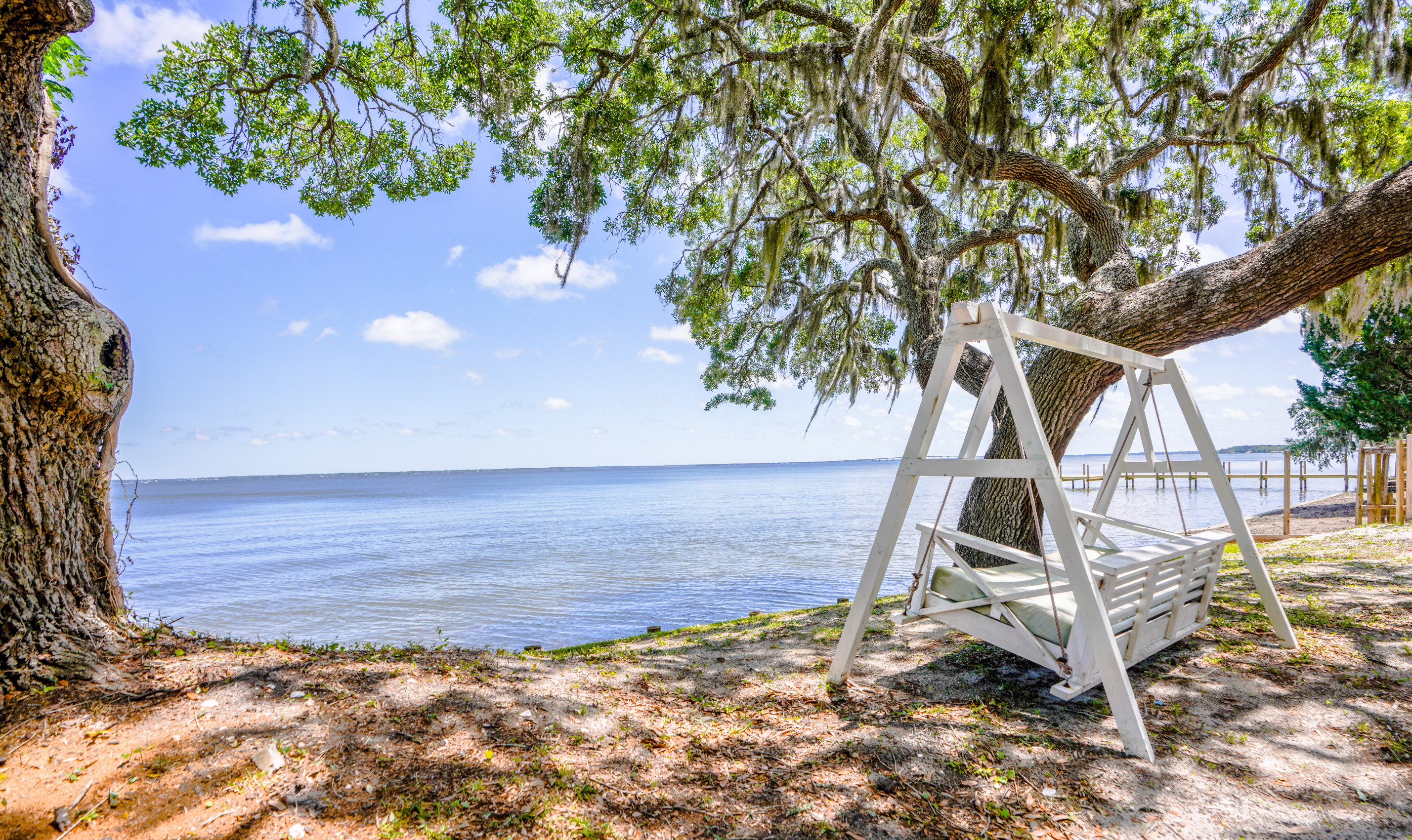 Photo of a white swing chair beneath a majestic oak tree overlooking the bay in Santa Rosa Beach