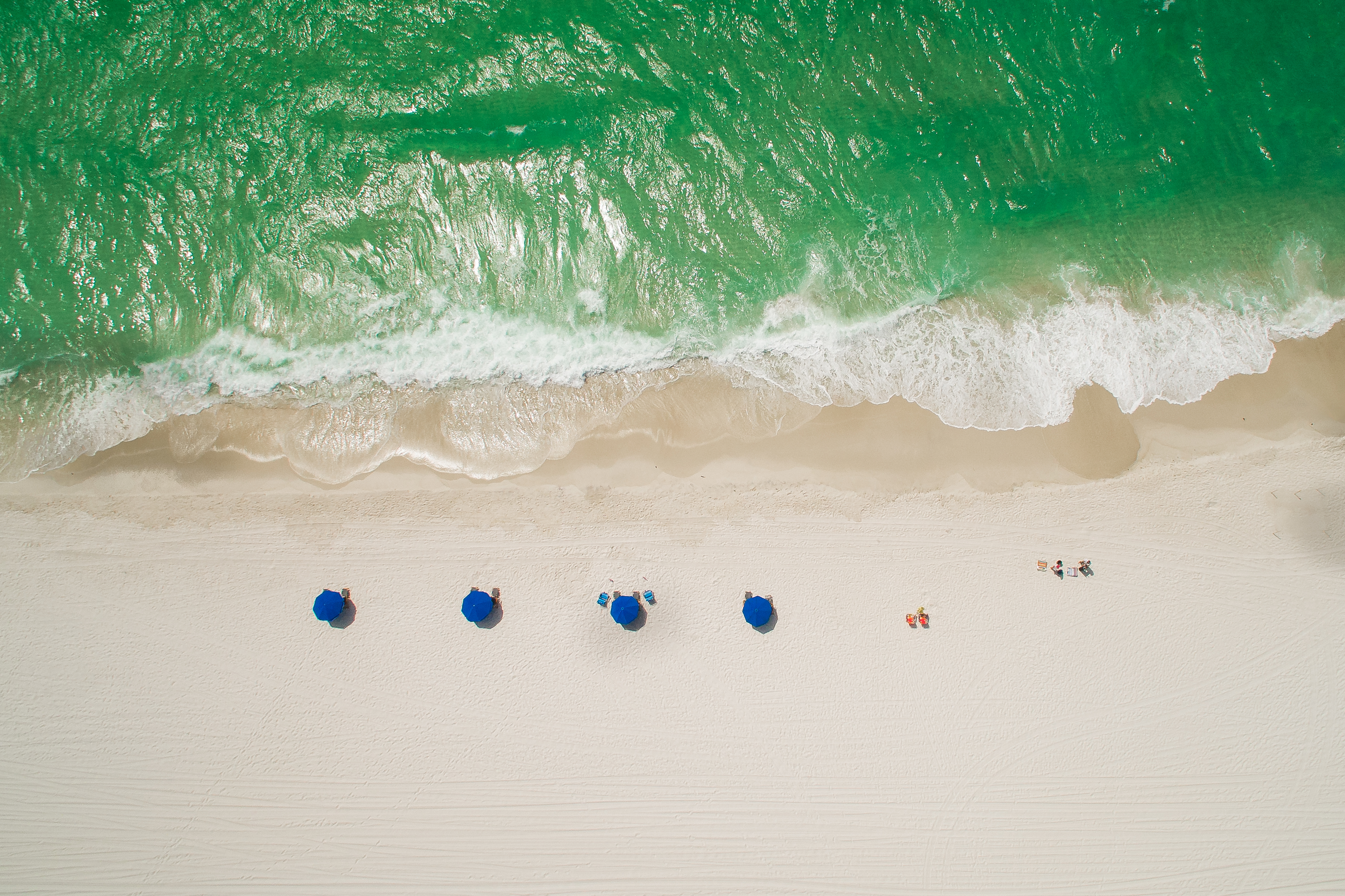 Gorgeous emerald green waves coming shore in front of beach chairs in Miramar Beach