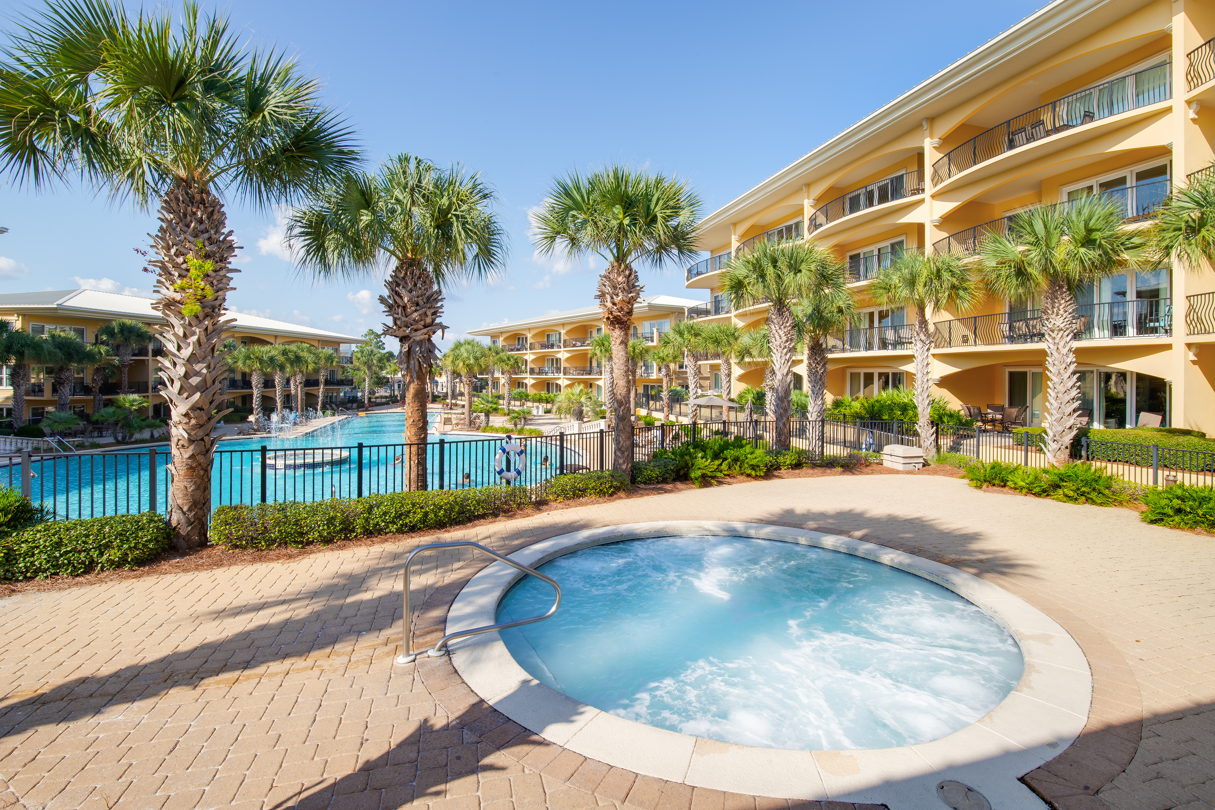 A shot of the outdoor pool and hot tub ensconced by palm trees at one of 30A's Gulf Front Condominiums